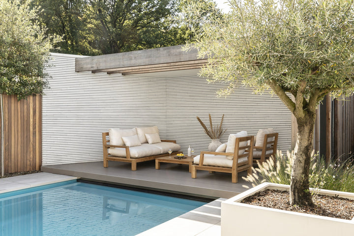 Daylounge-Gartenmöbel aus Teak unter einer Überdachung neben dem Pool.